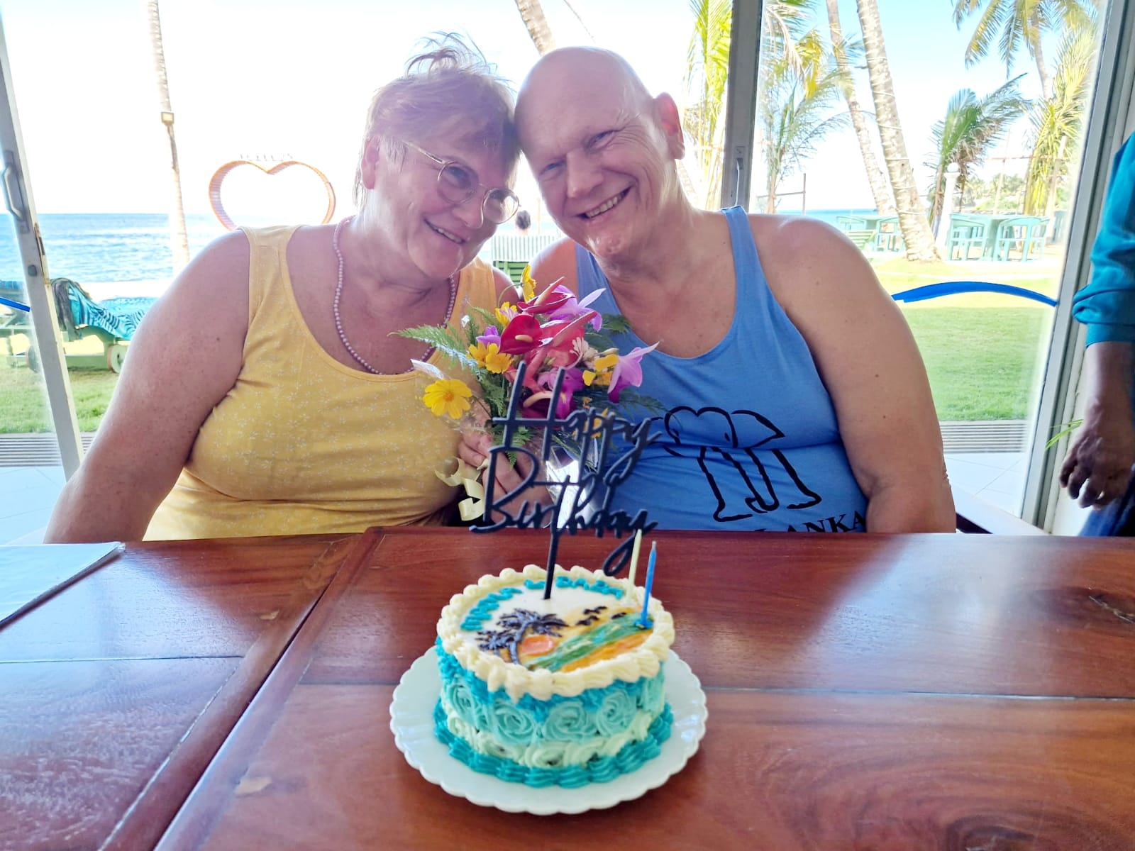 Guests celebrating a birthday with flowers and cake beside the Sri Lankan coast
